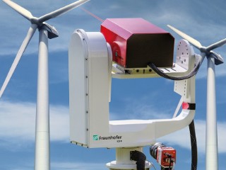 Ein Laservibrometer auf einem Schwenk-Neigekopf richtet seinen Messstrahl auf eine Windkraftanlage